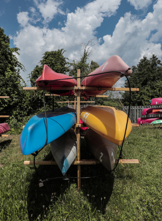 Four colourful canoes on a free-standing rack.